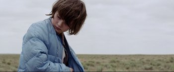 Movie still from “Cop Car” (2015), directed by Jon Watts – A young boy is standing in the middle of an empty field; Close Up shot, Low angle