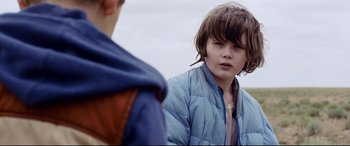 Movie still from “Cop Car” (2015), directed by Jon Watts – A young boy wearing a jacket and a tie; Close Up shot, Over the shoulder angle