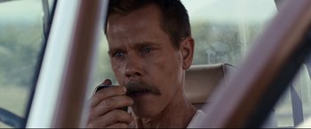 Movie still from “Cop Car” (2015), directed by Jon Watts – A person holding a cell phone; Close Up shot, Over the shoulder angle