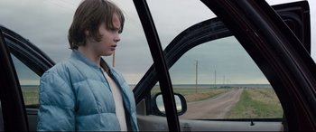 Movie still from “Cop Car” (2015), directed by Jon Watts – A young boy looking out the window of a car; Medium shot, Over the shoulder angle