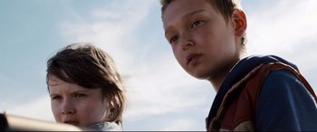 Movie still from “Cop Car” (2015), directed by Jon Watts – Two young children standing next to each other in front of a sky background; Close Up shot, Low angle