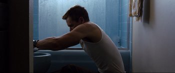 Movie still from “Cop Car” (2015), directed by Jon Watts – A man sitting on a bench in a bathroom; Medium shot, Low angle