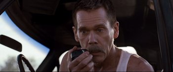 Movie still from “Cop Car” (2015), directed by Jon Watts – A person using a cell phone; Close Up shot, Over the shoulder angle