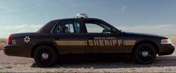 Movie still from “Cop Car” (2015), directed by Jon Watts – A police car parked on the side of the road; Wide shot, Low angle