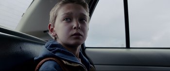 Movie still from “Cop Car” (2015), directed by Jon Watts – A boy sitting in the back seat of a car; Close Up shot, Low angle