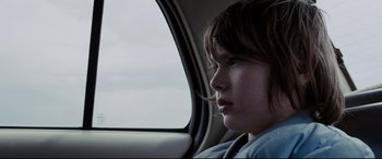 Movie still from “Cop Car” (2015), directed by Jon Watts – A young boy sitting in the back seat of a car looking out the window; Close Up shot, Over the shoulder angle