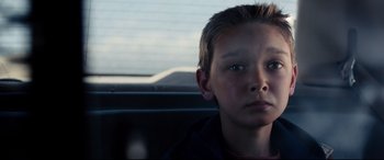 Movie still from “Cop Car” (2015), directed by Jon Watts – A boy sitting in the back seat of a car; Close Up shot, Over the shoulder angle
