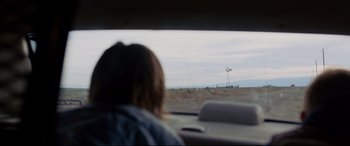 Movie still from “Cop Car” (2015), directed by Jon Watts – A woman sitting in the driver's seat of a car looking out the window; Extreme Wide shot, Over the shoulder angle