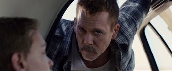 Movie still from “Cop Car” (2015), directed by Jon Watts – A person with a beard and mustache; Close Up shot, Over the shoulder angle