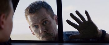 Movie still from “Cop Car” (2015), directed by Jon Watts – A person looking through a window; Close Up shot, Low angle