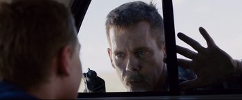 Movie still from “Cop Car” (2015), directed by Jon Watts – A man looking into a mirror while holding a gun; Close Up shot, Over the shoulder angle