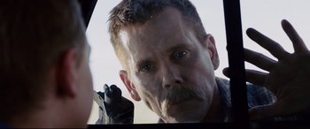 Movie still from “Cop Car” (2015), directed by Jon Watts – A person holding a gun in their hand; Close Up shot, Over the shoulder angle
