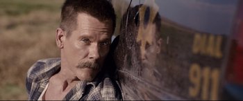 Movie still from “Cop Car” (2015), directed by Jon Watts – A person with a mustache; Close Up shot, Over the shoulder angle