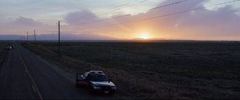 Movie still from “Cop Car” (2015), directed by Jon Watts – A car parked on the side of the road at sunset; Extreme Wide shot, Low angle