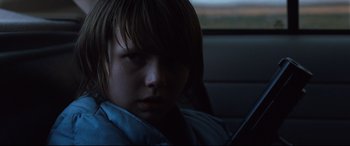 Movie still from “Cop Car” (2015), directed by Jon Watts – A young boy sitting in a car looking at the camera; Close Up shot, Over the shoulder angle