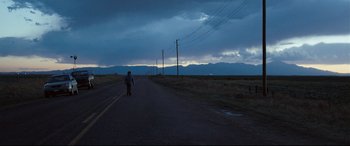Movie still from “Cop Car” (2015), directed by Jon Watts – A person walking down the middle of a road; Extreme Wide shot, Over the shoulder angle