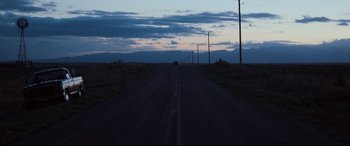 Movie still from “Cop Car” (2015), directed by Jon Watts – A car driving down a road at dusk; Extreme Wide shot, Low angle
