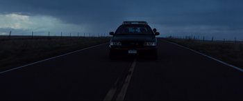 Movie still from “Cop Car” (2015), directed by Jon Watts – A police car driving down a road at night; Extreme Wide shot, Low angle