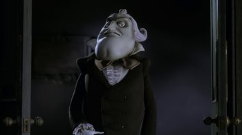 Movie still from “Corpse Bride” (2005), directed by Tim Burton – A man in a suit and tie with a strange face; Medium shot, Low angle