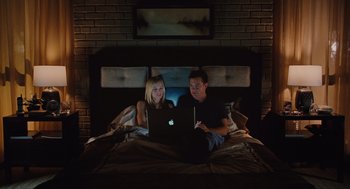 Movie still from “Couples Retreat” (2009), directed by Peter Billingsley – A man and a woman sitting on a bed looking at a laptop computer; Wide shot, Overhead angle