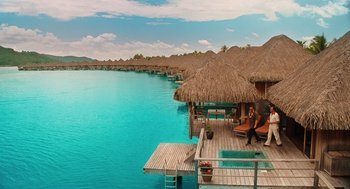 Movie still from “Couples Retreat” (2009), directed by Peter Billingsley – A woman sitting on a dock next to a raft; Extreme Wide shot, High angle