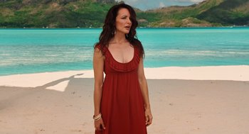 Movie still from “Couples Retreat” (2009), directed by Peter Billingsley – A woman standing on a beach wearing a red dress; Medium shot, High angle