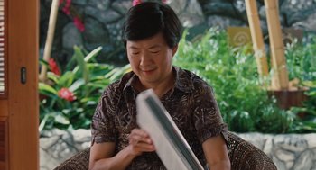 Movie still from “Couples Retreat” (2009), directed by Peter Billingsley – A man sitting in a chair holding a magazine; Close Up shot, Over the shoulder angle