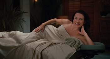 Movie still from “Couples Retreat” (2009), directed by Peter Billingsley – A woman laying in a bed with a blanket on her side; Medium shot, High angle