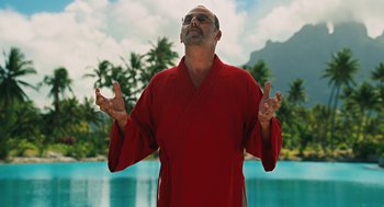 Movie still from “Couples Retreat” (2009), directed by Peter Billingsley – A man in a red robe standing in front of a body of water; Medium shot, Low angle