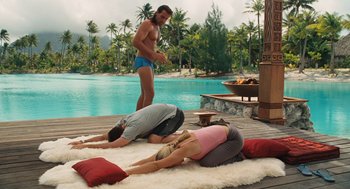 Movie still from “Couples Retreat” (2009), directed by Peter Billingsley – A man and a woman doing yoga in front of a pool; Wide shot, High angle