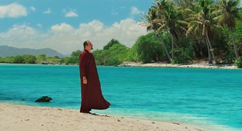 Movie still from “Couples Retreat” (2009), directed by Peter Billingsley – A man standing on the beach wearing a red robe; Extreme Wide shot, High angle