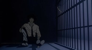 Movie still from “Cowboy Bebop: The Movie” (2001), directed by Yoshiyuki Takei – A man sitting on the ground in front of a jail cell; Wide shot, Low angle