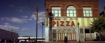 Movie still from “Coyote Ugly” (2000), directed by David McNally – A building that has a pizza sign on the side of the building; Extreme Wide shot, High angle