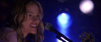 Movie still from “Coyote Ugly” (2000), directed by David McNally – A person holding a microphone; Close Up shot, Low angle