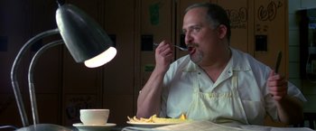 Movie still from “Coyote Ugly” (2000), directed by David McNally – A man sitting at a table with a plate of food in front of him; Close Up shot, Low angle