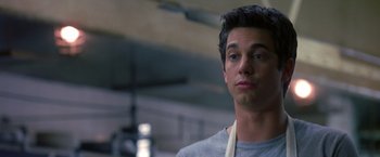 Movie still from “Coyote Ugly” (2000), directed by David McNally – A man with a beard is wearing an apron; Close Up shot, Over the shoulder angle