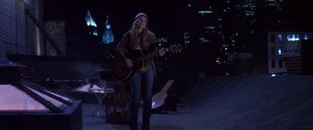 Movie still from “Coyote Ugly” (2000), directed by David McNally – A woman is playing a guitar on a stage in the dark; Wide shot, Low angle