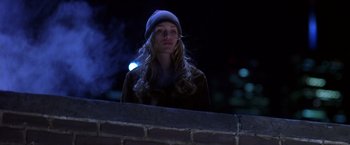 Movie still from “Coyote Ugly” (2000), directed by David McNally – A woman wearing a hat standing next to a brick wall at night; Medium shot, Low angle