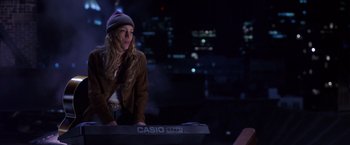 Movie still from “Coyote Ugly” (2000), directed by David McNally – A woman standing next to a keyboard in a dark room; Medium shot, High angle