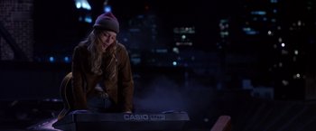 Movie still from “Coyote Ugly” (2000), directed by David McNally – A woman standing next to a keyboard in a dark room; Medium shot, High angle
