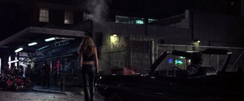 Movie still from “Coyote Ugly” (2000), directed by David McNally – A woman walking down a street next to an old car; Wide shot, Over the shoulder angle