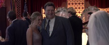 Movie still from “Coyote Ugly” (2000), directed by David McNally – A man standing next to a woman in front of a flower arrangement; Medium shot, Over the shoulder angle