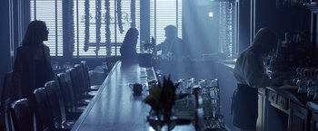 Movie still from “Coyote Ugly” (2000), directed by David McNally – Two people are sitting at a bar in the dark; Wide shot, Low angle