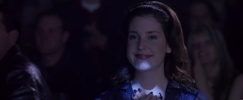 Movie still from “Coyote Ugly” (2000), directed by David McNally – A woman is smiling and holding a light up necklace; Close Up shot, Over the shoulder angle