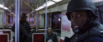 Movie still from “Cradle 2 the Grave” (2003), directed by Andrzej Bartkowiak – A man in a helmet is sitting on a train; Close Up shot, Over the shoulder angle