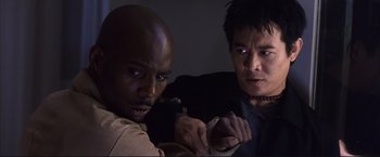 Movie still from “Cradle 2 the Grave” (2003), directed by Andrzej Bartkowiak – Two men are looking at a cell phone in a dark room; Close Up shot, High angle