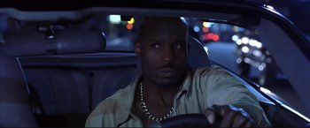 Movie still from “Cradle 2 the Grave” (2003), directed by Andrzej Bartkowiak – A man sitting in the driver's seat of a car at night; Close Up shot, Low angle
