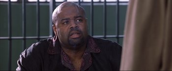 Movie still from “Cradle 2 the Grave” (2003), directed by Andrzej Bartkowiak – A man with a beard is sitting in front of bars; Close Up shot, High angle