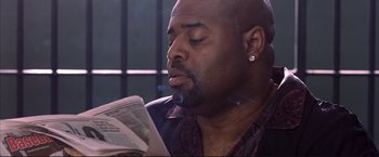 Movie still from “Cradle 2 the Grave” (2003), directed by Andrzej Bartkowiak – A man is smoking while reading a newspaper; Close Up shot, Low angle