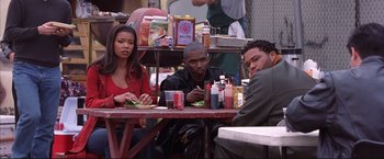 Movie still from “Cradle 2 the Grave” (2003), directed by Andrzej Bartkowiak – A group of people sitting at a table eating food; Medium shot, High angle